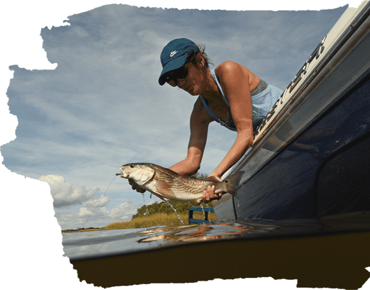 Angler releasing a freshly caught redfish back into the water from the side of a boat